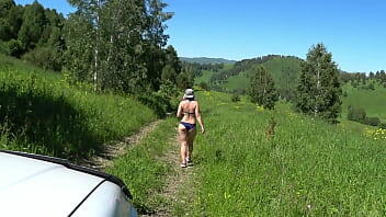 A mature blonde with a gorgeous ass in a swimsuit walks along the road and drives car drivers crazy. Voyeur in a public place outdoors peeping.
