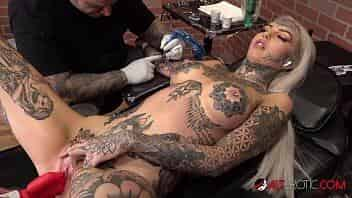 Beautiful busty blonde uses a toy while having her arm tattooed