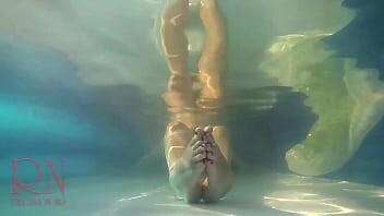 Elegant and flexible babe, swimming underwater in the outdoor swimming pool.